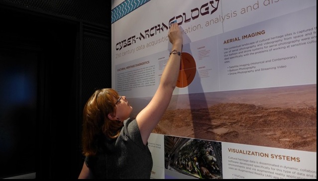 CURII Kat Huggins in front of Ashley M. Richter's Cyber-Archaeology Panels at the event. 